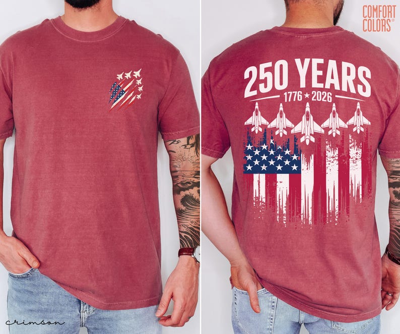 May include: A crimson short-sleeve t-shirt featuring a small graphic on the front left chest of fighter jets and a distressed American flag. The back displays the text 250 YEARS 1776-2026 above five fighter jets and a large distressed American flag.