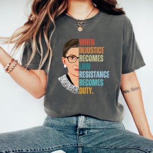 May include: A gray t-shirt with a vintage-style graphic of Ruth Bader Ginsburg and the text "When injustice becomes law, resistance becomes duty."
