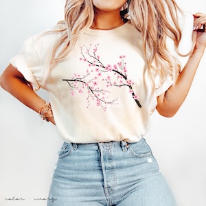 May include: A white t-shirt with a pink and brown cherry blossom branch design. The text "color: ivory" is at the bottom of the image.