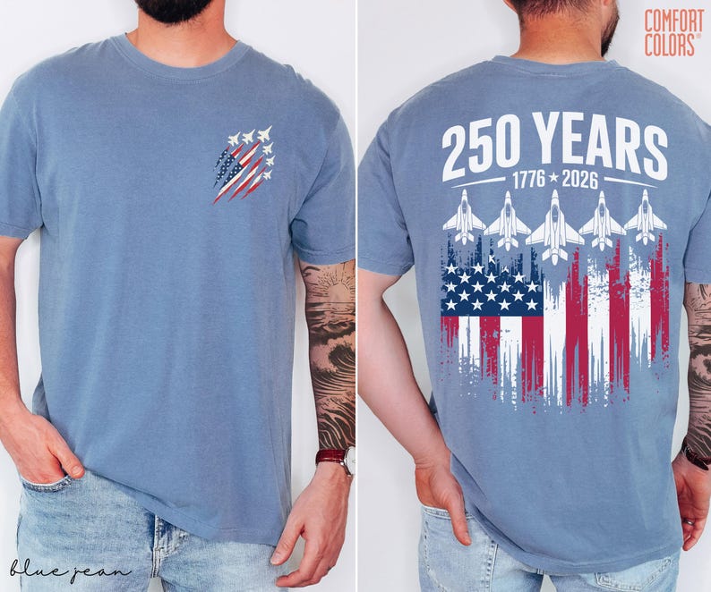 May include: A blue short-sleeve t-shirt featuring a small graphic on the front left chest of fighter jets over a distressed American flag. The back displays the text 250 YEARS 1776-2026 above five fighter jets and a large distressed American flag.
