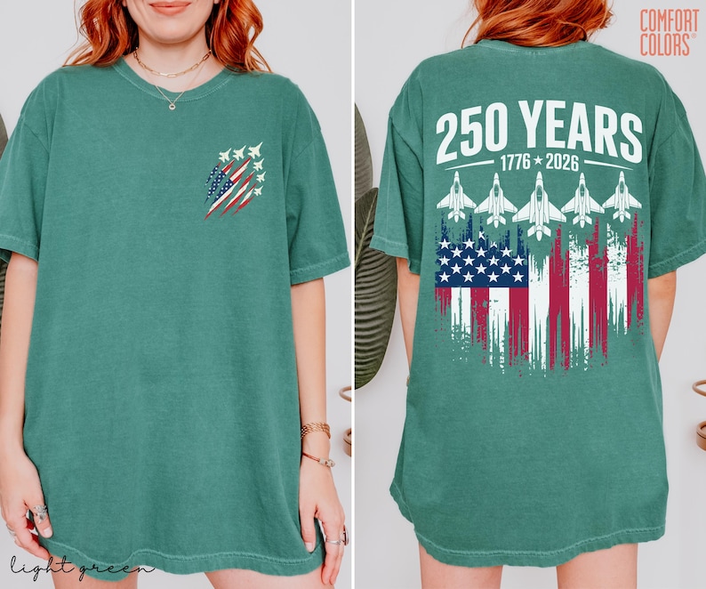 May include: A sage green short-sleeve t-shirt featuring a small graphic on the front left chest of a distressed American flag with fighter jets. The back displays the text 250 YEARS 1776-2026 above five fighter jets and a large distressed American flag.