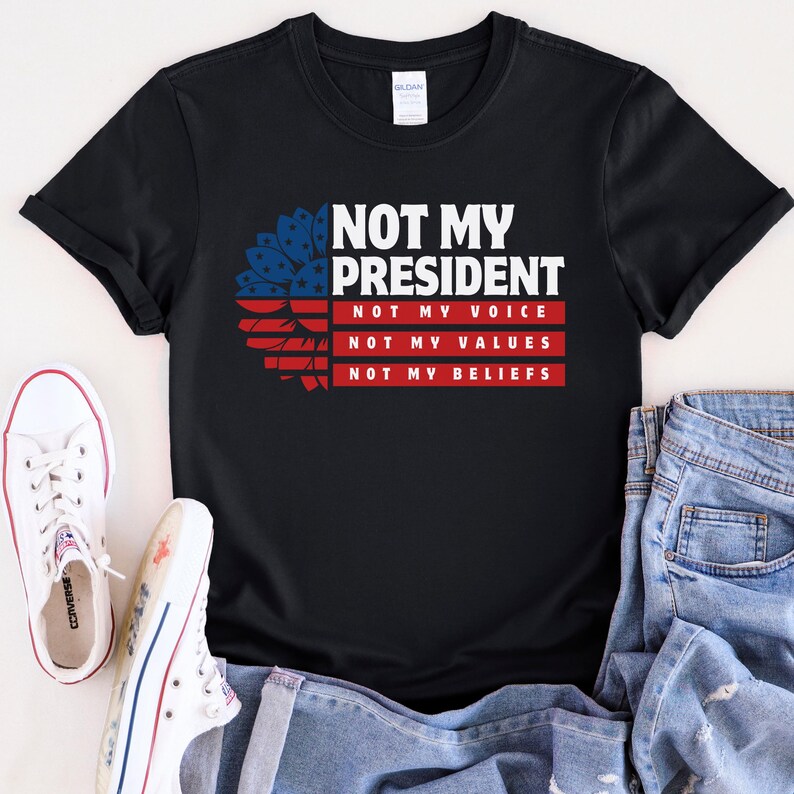 May include: Black t-shirt with a red, white, and blue sunflower graphic and the text "Not My President, Not My Voice, Not My Values, Not My Beliefs".