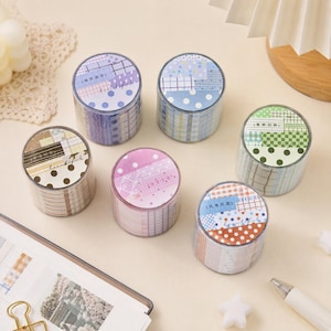 May include: Six rolls of decorative adhesive tape arranged in a cluster. Each roll features a unique color palette including purple, blue, green, brown, pink, and orange, with patterns such as polka dots, grids, and stripes, and printed text.