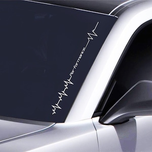 May include: A white vinyl decal with a stylized heartbeat graphic and the word "Performance" on a black car windshield.