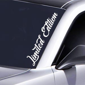 May include: White vinyl sticker with the text "Limited Edition" in a cursive font. The sticker is applied to the windshield of a car.