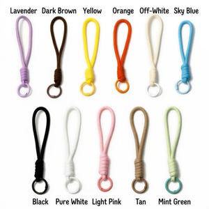 Peut inclure: Une collection de onze porte-cl&eacute;s de diff&eacute;rentes couleurs : lavande, marron fonc&eacute;, jaune, orange, blanc cass&eacute;, bleu ciel, noir, blanc pur, rose clair, beige et vert menthe. Chaque porte-cl&eacute;s est dot&eacute; d'une boucle et d'un anneau m&eacute;tallique.