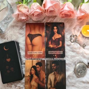 Peut inclure: Un jeu de cartes de tarot avec quatre cartes affichées, présentant des illustrations de personnages et du texte. Les cartes sont disposées sur une surface blanche moelleuse, avec des roses roses et un masque argenté en arrière-plan. Le jeu est noir avec un croissant de lune et un cœur.