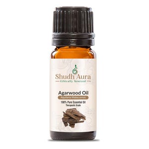 May include: A brown glass bottle with a black cap containing Agarwood Oil. The label is white with green text and a green logo. The text on the label reads "Shudh Aura Ethically Sourced Agarwood Oil Aquilaria Malaccensis 100% Pure Essential Oil Therapeutic Grade".