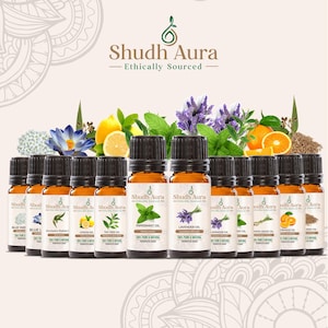 Puede incluir: Una colección de botellas de aceites esenciales con tapas negras y etiquetas blancas, que muestran la marca "Shudh Aura" y aceites como Lavanda y Menta. Botánicos frescos, incluyendo lavanda, limones y naranjas, están dispuestos detrás de las botellas.