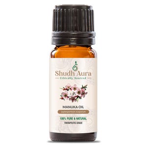 May include: A brown glass bottle with a black cap, labeled "Shudh Aura Ethically Sourced Manuka Oil Leptospermum scoparium 100% PURE & NATURAL THERAPEUTIC GRADE". The label features a green leaf design and a white flower.