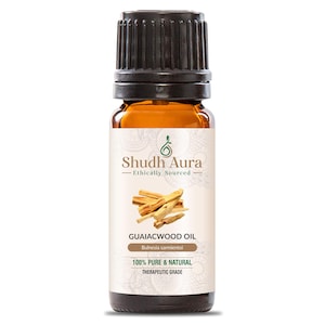 Puede incluir: Una botella de vidrio marrón con una tapa negra, etiquetada "Shudh Aura Ethically Sourced Guaiacwood Oil Bulnesia sarmientoi 100% Pure & Natural Therapeutic Grade". La botella contiene un líquido marrón claro y está sobre un fondo blanco.