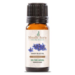 May include: A small amber glass bottle with a black cap, labeled "Shudh Aura - Ethically Sourced" and "Tansy Blue Oil - Tanacetum annuum - 100% Pure & Natural - Therapeutic Grade". The label also features a green leaf design and an image of blue tansy flowers.