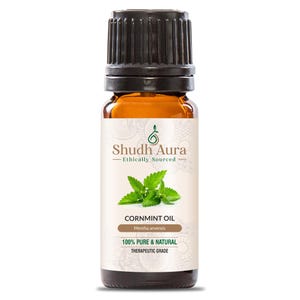 May include: A brown glass bottle of Shudh Aura Cornmint Oil. The label features the brand name, a sprig of mint, and the text "100% Pure & Natural Therapeutic Grade." The bottle has a black cap and is filled with a golden liquid.
