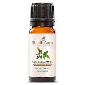 May include: A brown glass bottle with a black cap, labeled "Shudh Aura - Ethically Sourced" and "Copaiba Balsam Oil". The label also includes the botanical name "Copaifera reticulata syn C. officinalis" and states that the oil is "100% Pure & Natural" and "Therapeutic Grade".
