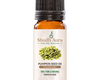 May include: A brown glass bottle of pumpkin seed oil with a black cap. The label features the text "Shudh Aura" and "Pumpkin Seed Oil" with the scientific name "Cucurbita pepo". The label also states "100% Pure & Natural" and "Therapeutic Grade".