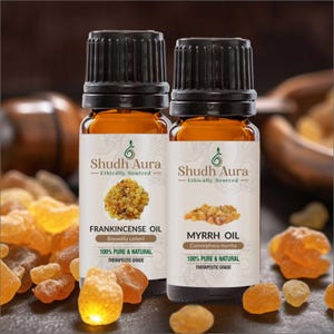 May include: Two amber glass bottles of essential oil with black caps. One label reads "Frankincense Oil" and the other "Myrrh Oil". The labels also state "100% Pure & Natural". The brand name "Shudh Aura" is visible.