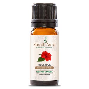 May include: A brown glass bottle with a black cap, labeled "Shudh Aura - Ethically Sourced" and "Hibiscus Oil - Hibiscus sabdariffa L. 100% Pure & Natural Therapeutic Grade". The label features a red hibiscus flower.