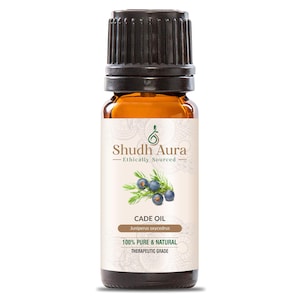 Könnte beinhalten: Kleine bernsteinfarbene Glasflasche mit Cade-Öl und schwarzem Verschluss. Das Etikett zeigt "Shudh Aura - Ethically Sourced" und "Cade Oil" mit dem wissenschaftlichen Namen "Juniperus oxycedrus". Das Etikett besagt auch "100% Pure & Natural Therapeutic Grade".