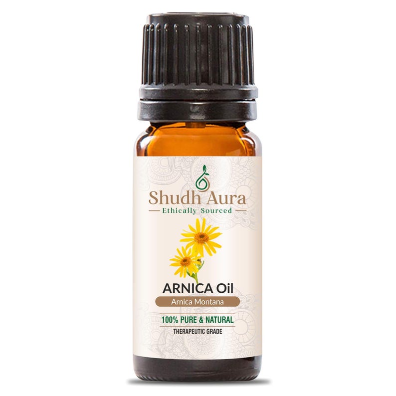May include: A brown glass bottle with a black cap, labeled "Shudh Aura Ethically Sourced ARNICA Oil Arnica Montana 100% PURE & NATURAL THERAPEUTIC GRADE". The label features a yellow flower with green leaves.