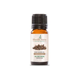 May include: A small brown glass bottle with a black cap, containing Rose Wood Oil. The label reads "Shudh Aura Ethically Sourced" and "Rose Wood Oil Aniba rosacaodora 100% Pure & Natural Therapeutic Grade".