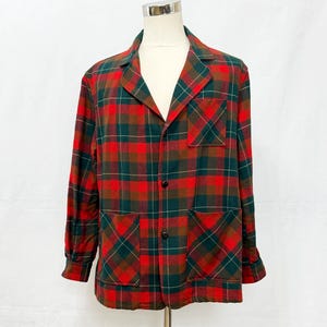 Peut inclure: Une chemise à manches longues boutonnée avec un motif à carreaux rouge, vert foncé et marron. La chemise présente un col à revers, une poche poitrine et deux poches avant inférieures, le tout confectionné dans le même tissu à carreaux.