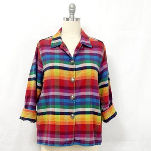 May include: A colorful plaid button-down shirt with three-quarter sleeves. The shirt features a vibrant rainbow of colors, including red, yellow, green, blue, and purple. It has a collared neckline and silver-toned buttons.