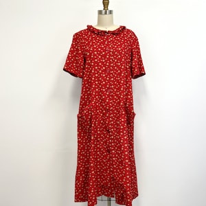 以下が含まれることがあります： 白い花柄の赤いドレスで、フリル襟が付いています。ドレスは半袖で、ポケットが2つ付いています。