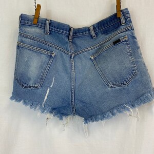 Pu&ograve; includere: Un paio di pantaloncini di jeans blu chiaro con orlo sfrangiato. I pantaloncini hanno una tasca posteriore con un piccolo logo.
