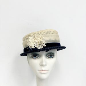 May include: A white straw hat with a navy blue velvet band and a white lace flower accent.