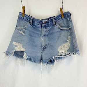 Pu&ograve; includere: Shorts di jeans consumati con bordi sfrangiati e pi&ugrave; strappi. I pantaloncini sono di colore blu chiaro e hanno un vita alta.