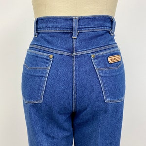 May include: A pair of blue denim jeans with a high waist and a brown leather patch on the back right pocket that says "BRAYTON".