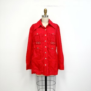 May include: A red long-sleeved button-up shirt with silver hardware and two large pockets on the front.