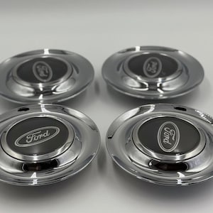 Puede incluir: Cuatro tapacubos Ford cromados. Cada tapacubo tiene un centro negro con el logotipo de Ford en blanco. Los tapacubos son de forma ovalada con una superficie brillante y reflectante.