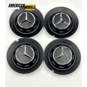 Op de afbeelding: Set van vier zwarte wieldoppen met een zilveren Mercedes-Benz-logo. De doppen hebben een gestructureerd oppervlak en een verhoogde rand rond het logo.