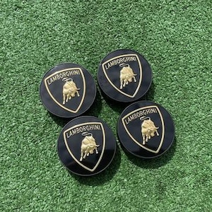 May include: Four black and gold Lamborghini car center caps with a bull logo.