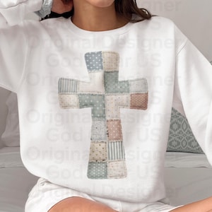 May include: White sweatshirt featuring a patchwork cross design. The cross is composed of various fabric patterns in pastel colors, including polka dots, stripes, and floral prints. The sweatshirt is a comfortable, casual style.