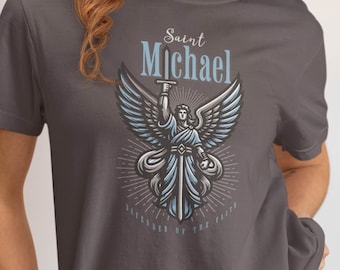 May include: Graphite-colored t-shirt featuring a graphic of Saint Michael with wings, a sword, and the text "Saint Michael" above the image. Below the image is the text "Defender of the Faith".