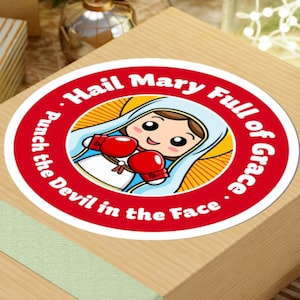 May include: A red and white round sticker with a cartoon image of the Virgin Mary wearing boxing gloves. The text on the sticker reads "Hail Mary Full of Grace. Punch the Devil in the Face."