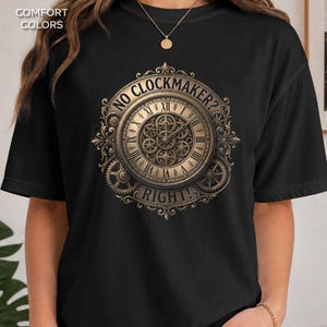 May include: A black t-shirt featuring a gold-toned graphic of a clock face with visible internal gears and ornate filigree detailing. The text "NO CLOCKMAKER?" is arched above the clock, and the word "RIGHT!" is positioned below the clock face.
