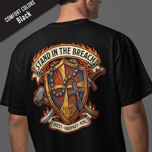 May include: Black t-shirt with a graphic design featuring a shield, rosary, cross, and tools. The design includes the text "STAND IN THE BREACH," "EZEKIEL 22:30," and "PRIEST - PROPHET - KING." The shirt is labeled "COMFORT COLORS Black."