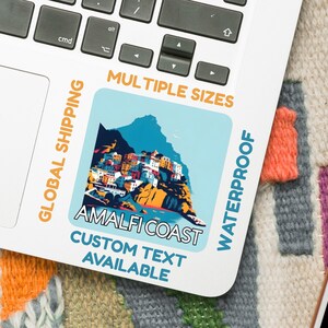 May include: A square sticker with a vibrant illustration of the Amalfi Coast, labelled "AMALFI COAST" and "CUSTOM TEXT AVAILABLE". The sticker is on a laptop, with text that says "MULTIPLE SIZES" and "WATERPROOF".