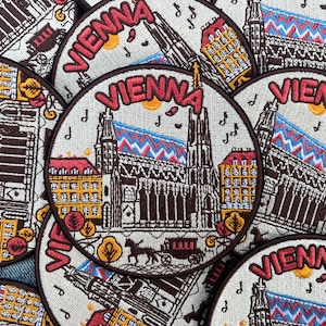 May include: Circular embroidered patches featuring the word "VIENNA" in red, with detailed illustrations of Vienna landmarks. The patches include images of buildings, musical notes, and a horse-drawn carriage, all in a vintage style.