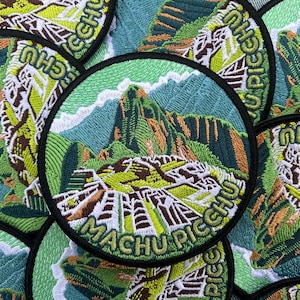 May include: Embroidered patch featuring a detailed depiction of Machu Picchu, with green mountains, blue skies, and the text "Machu Picchu" in white. The patch has a black border and is circular.