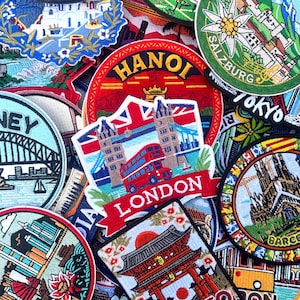 Könnte beinhalten: Eine Sammlung gestickter Aufnäher mit berühmten Wahrzeichen und Städtenamen. Aufnäher mit "Sydney", "London", "Hanoi", "Tokyo" und "Barcelona". Die Aufnäher sind farbenfroh und detailliert, mit Bildern von Brücken, Bussen und Tempeln.