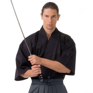 May include: A person wearing a black martial arts uniform holds a katana sword in a traditional grip.