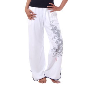 May include: White pants with a black dragon design on the right leg. The pants have a navy blue trim at the bottom.