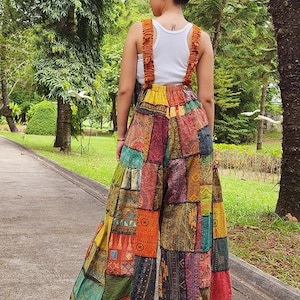 May include: A pair of wide-leg patchwork pants with a colorful, multi-patterned design. The pants have a high waist and are made from a variety of fabrics, including cotton and silk. The pants are a vibrant mix of colors, including red, orange, yellow, green, blue, and purple.