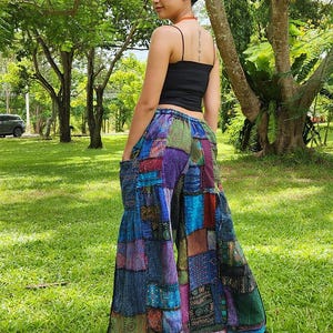 May include: Patchwork wide-leg pants with a variety of colors and patterns, including blue, purple, green, and brown. The pants have a loose fit and a wide leg.