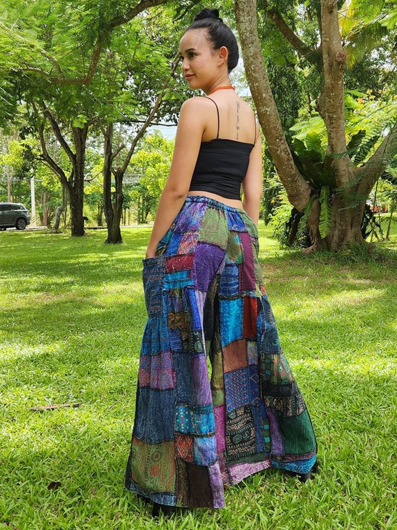 May include: Patchwork wide-leg pants with a variety of colors and patterns, including blue, purple, green, and brown. The pants have a loose fit and a wide leg.