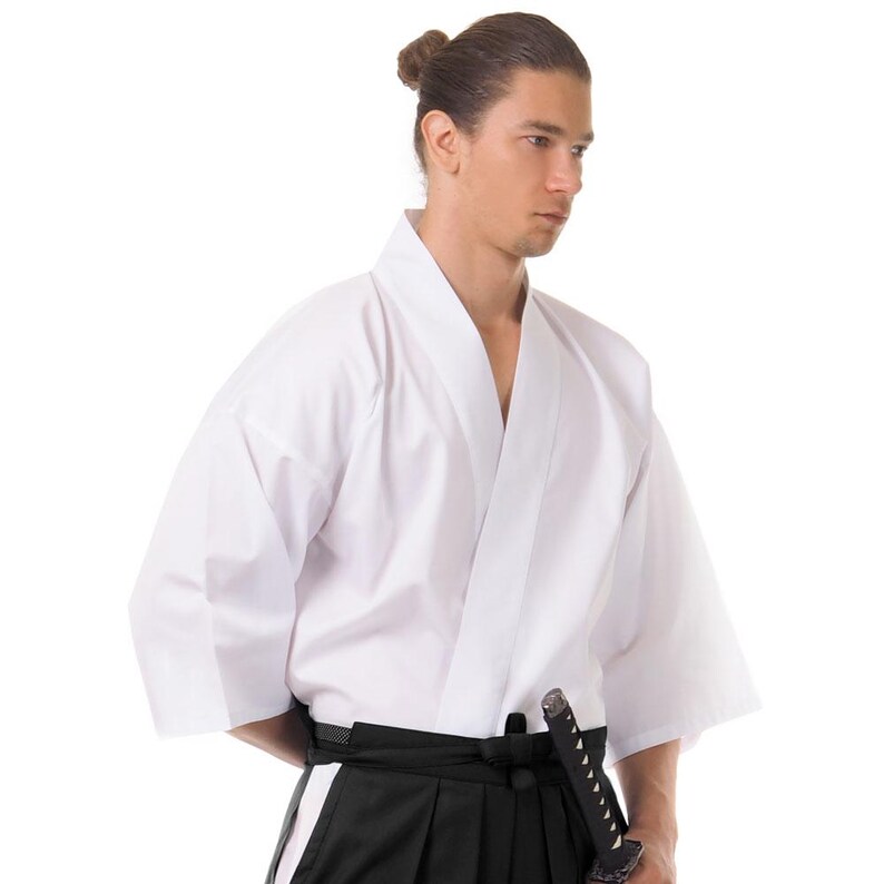 Puede incluir: Uniforme blanco de artes marciales con cintur&oacute;n negro y espada. El uniforme es de estilo japon&eacute;s tradicional.